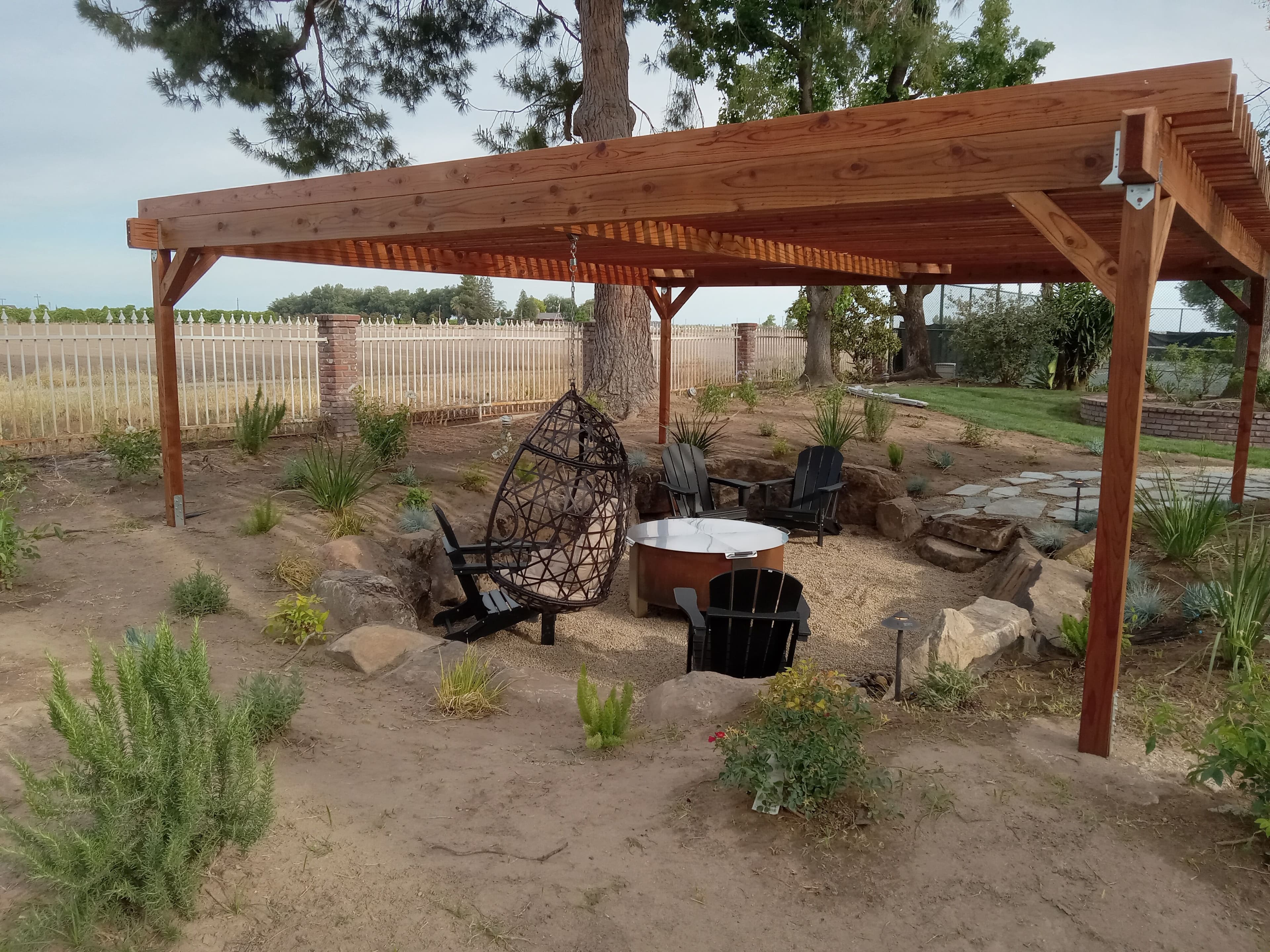 Wooden pergola with a cozy seating area and landscaping in a serene garden setting.