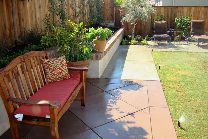 Cozy outdoor patio with wooden bench, landscaped garden, and relaxing lounge chairs.