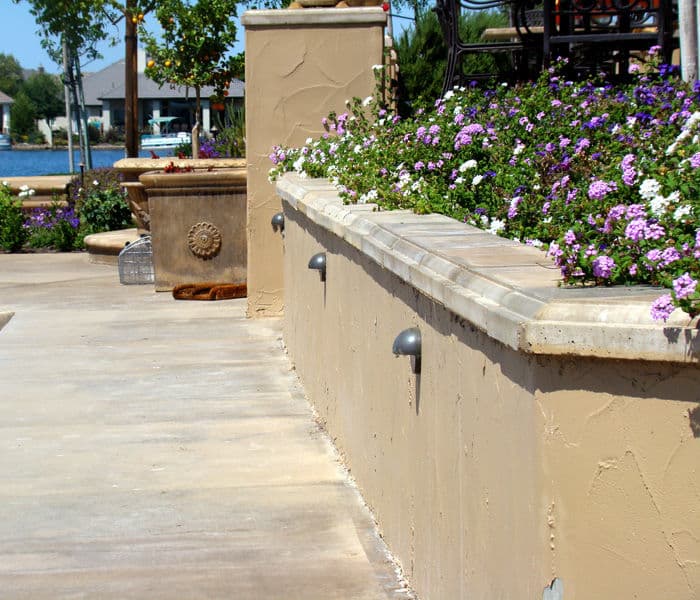Landscape featuring blooming flowers and decorative stone wall by a lakeside promenade.