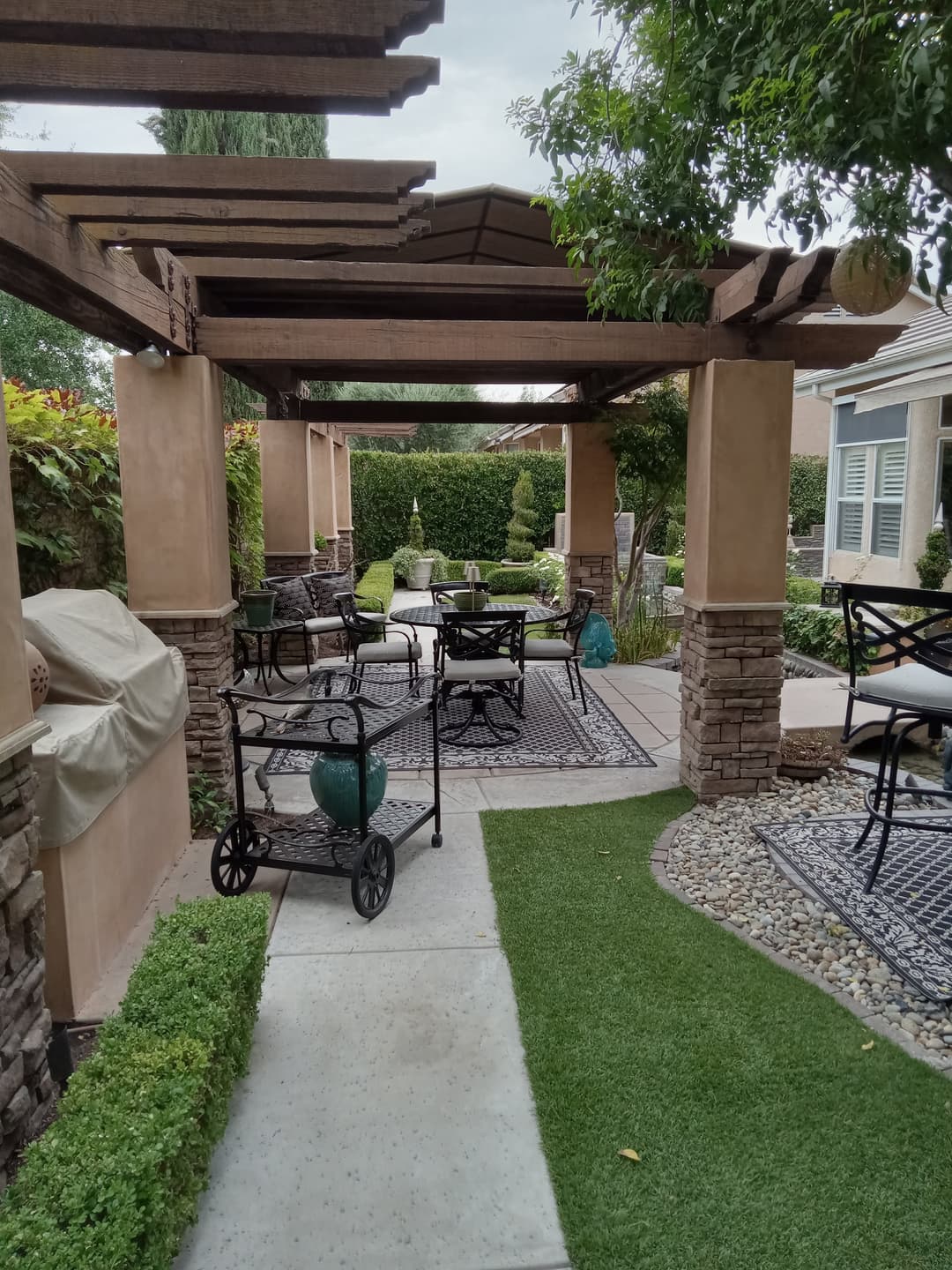 Beautiful outdoor patio with stone pillars, seating area, and lush greenery. Ideal for relaxation.