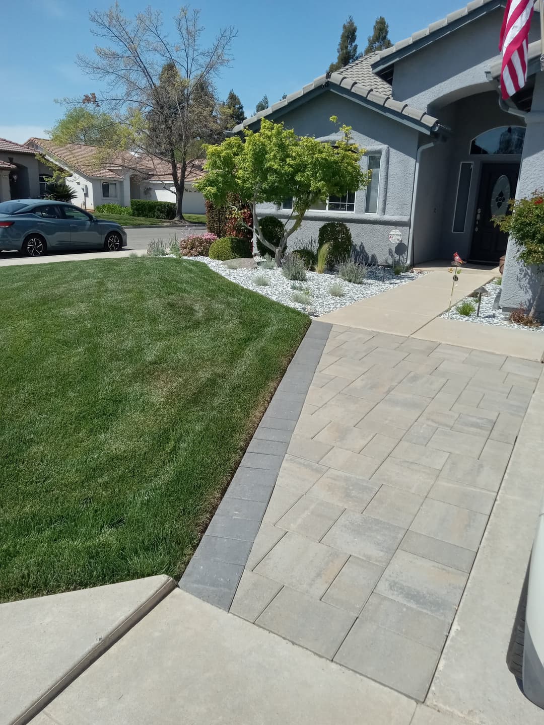 Well-maintained front yard with lush grass, stone pathway, and decorative landscaping.