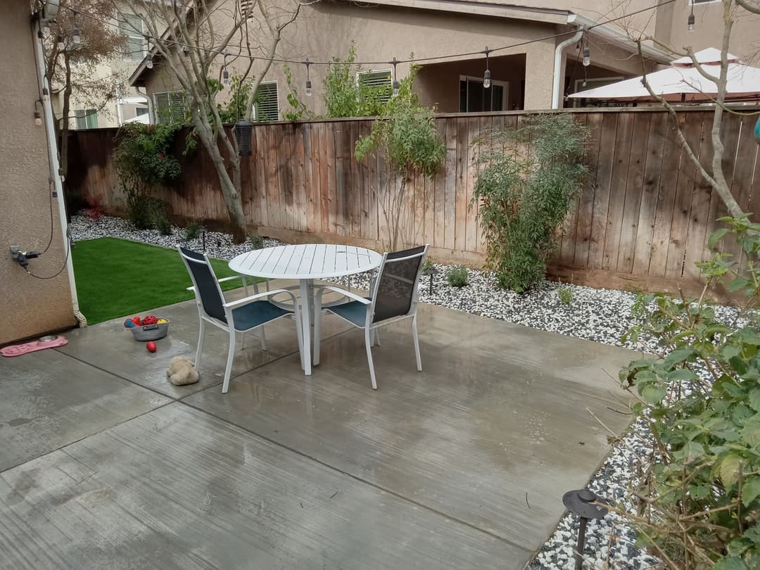 Cozy backyard patio with a white table, chairs, and decorative stone landscaping.