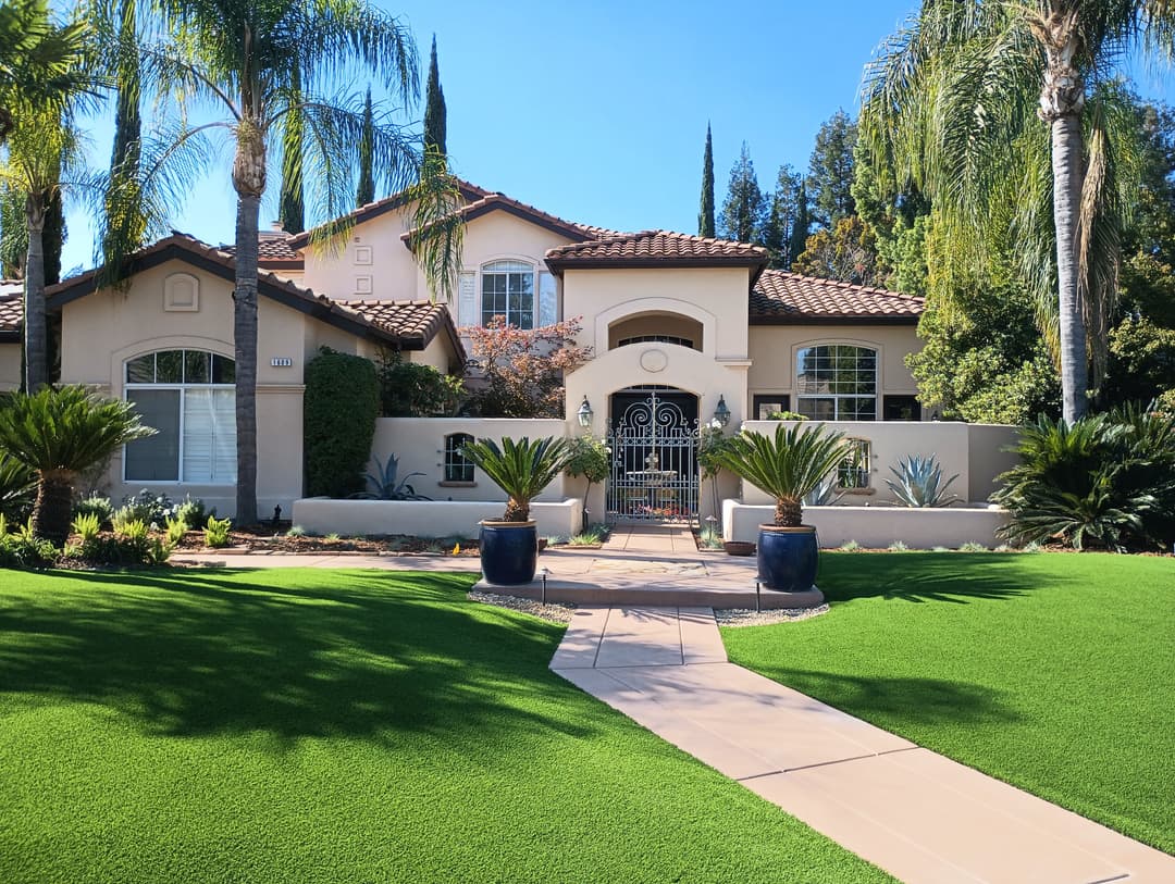 Elegant Mediterranean-style home with palm trees and lush green landscaping.