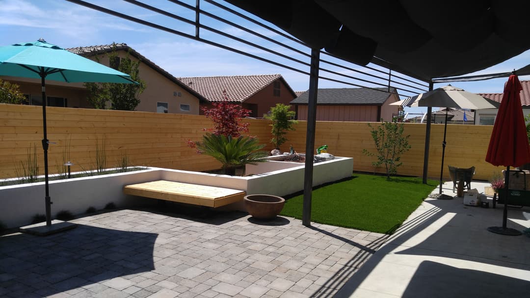 Modern backyard oasis featuring landscaped areas, seating, and shading umbrellas.
