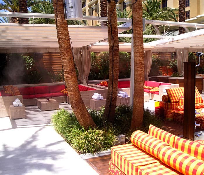 Luxurious outdoor lounge area with vibrant seating, palm trees, and shaded cabanas.