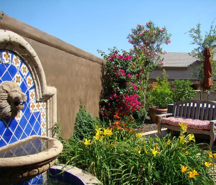 Colorful garden with blooming flowers, a stone fountain, and a cozy seating area.