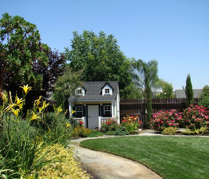 Charming garden with a playhouse surrounded by colorful flowers and greenery.