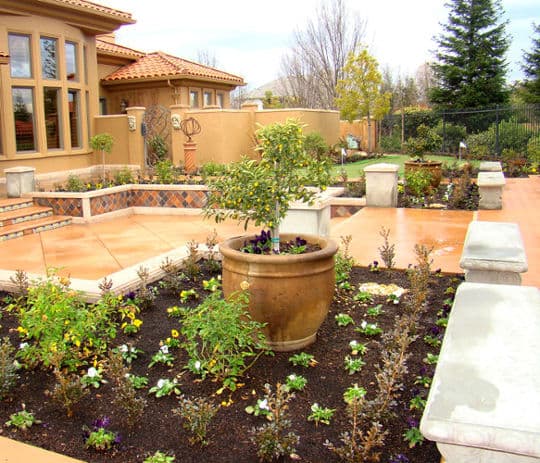 Lush garden with flower beds and a decorative pot, enhancing a luxurious home landscape.