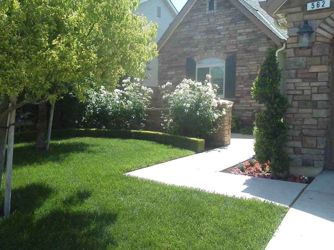 Beautiful stone house with well-maintained lawn and flower beds, enhancing curb appeal.