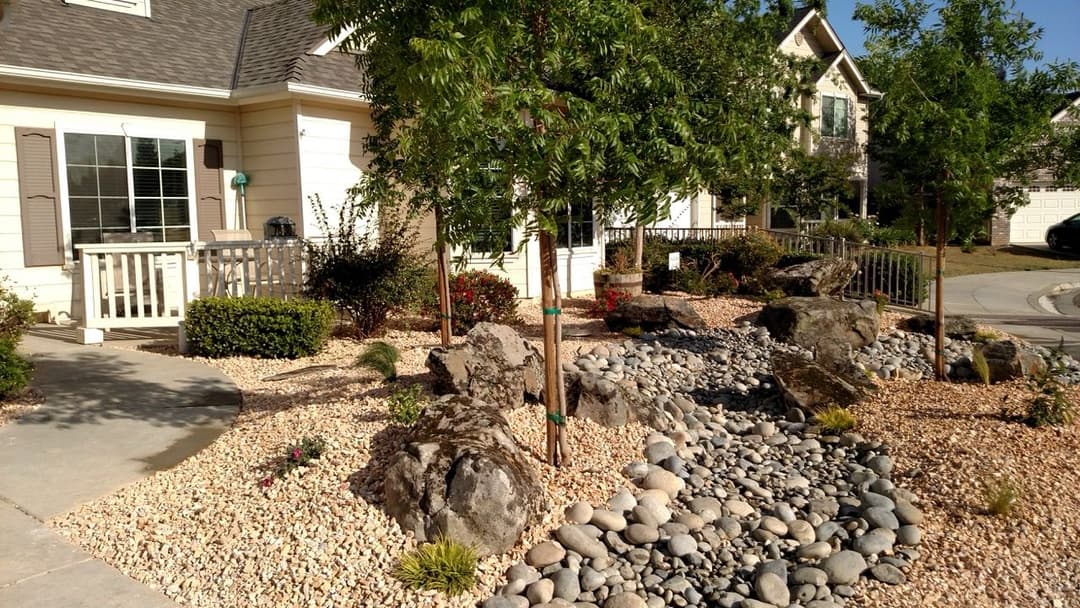 Zen garden landscape with rocks, pebbles, and greenery creating a serene outdoor space.