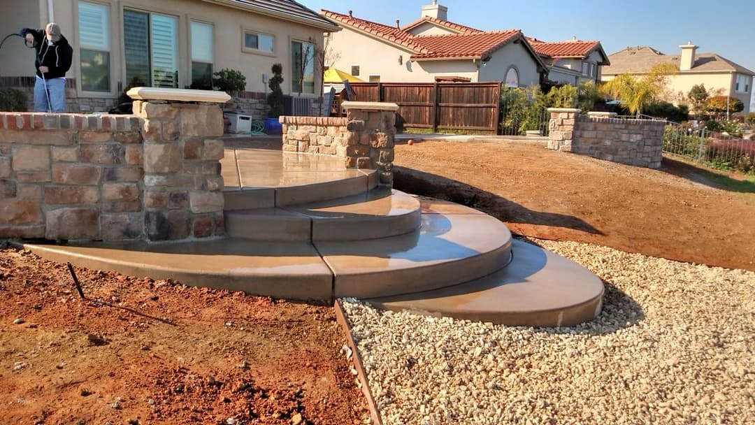 Curved concrete steps and stone walls in a residential landscaping project.